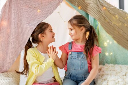 happy girls lying in kids tent and talking at homeの写真素材