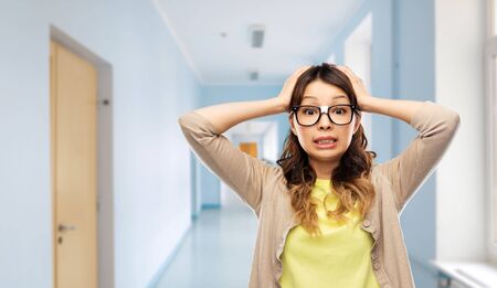 stressed female student holding to head at schoolの写真素材