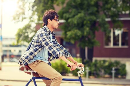Young hipster man with bag riding fixed gear bikeの写真素材