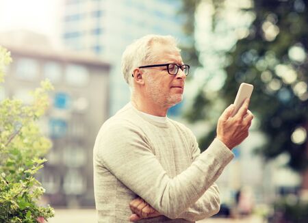 Senior man texting message on smartphone in cityの写真素材