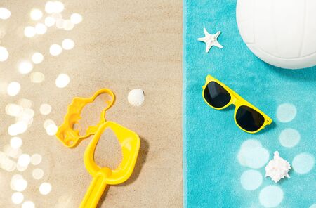 vacation, travel and summer holidays concept - yellow sunglasses, sand toys, seashells and...