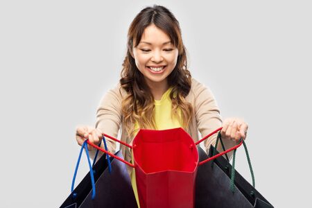 happy asian woman with open shopping bagsの写真素材