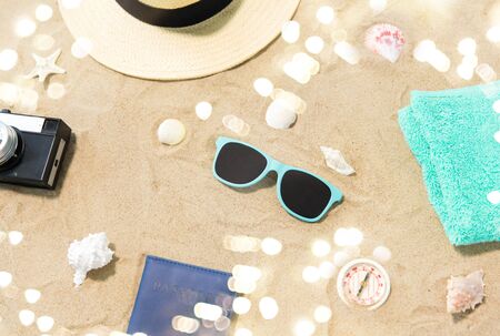 Camera, passport, sunglasses and hat on beach sandの写真素材