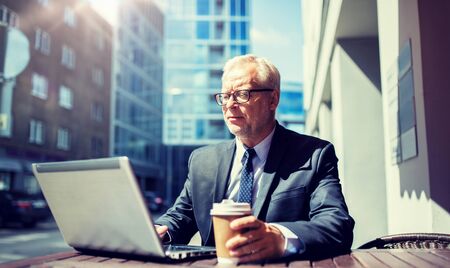 Senior businessman with laptop drinking coffee