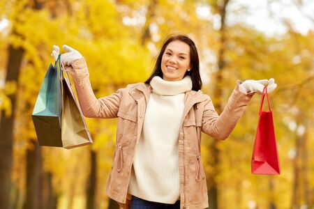 Woman with shopping bags in autumn parkの写真素材