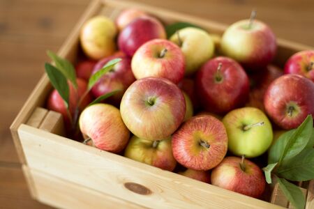 Ripe apples in wooden box on tableの写真素材