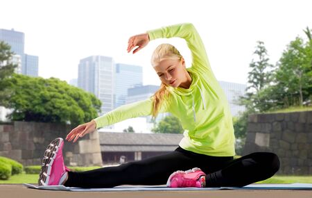 Woman stretching on exercise mat at city park