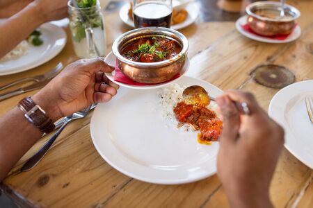 african man eating with friends at restaurantの写真素材