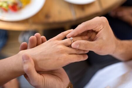 man giving diamond ring to woman at restaurant
