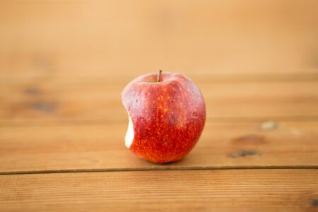 ripe red bitten apple on wooden tableの写真素材