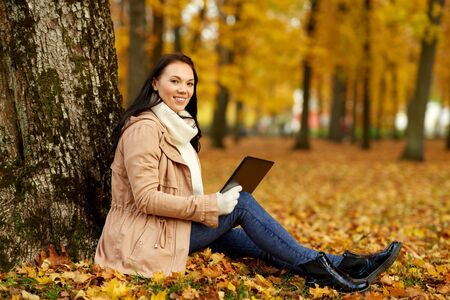 woman with tablet computer at autumn parkの写真素材