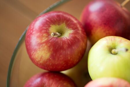 fruits, food and harvest concept - ripe apples in glass bowl on wooden table