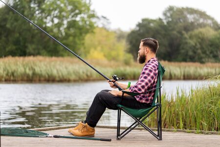 leisure and people concept - bearded fisherman with fishing rodの写真素材