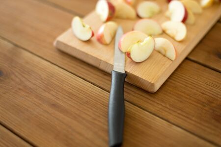 fruits, food cooking and eating concept - sliced apples and kitchen knife on wooden cutting boardの写真素材