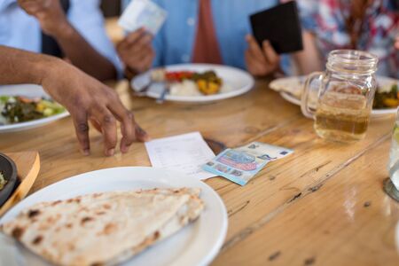 male hand with bill and money on restaurant tableの写真素材