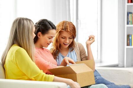 teenage girls or friends opening parcel boxの写真素材