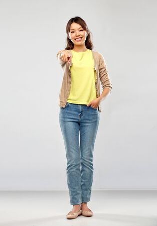asian woman pointing to you over grey backgroundの写真素材