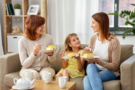 mother, daughter and grandmother eating cakeの写真素材