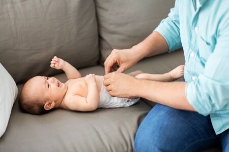middle aged father changing babys diaper at home
