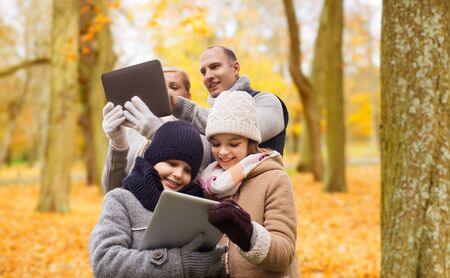 Happy family with tablet pc in autumn park