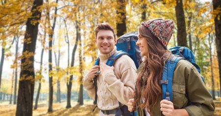 Smiling couple with backpacks hiking in autumn