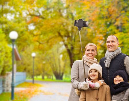 happy family with smartphone and monopod in parkの写真素材