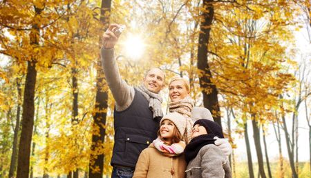 happy family with camera in autumn parkの写真素材
