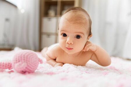 sweet baby girl lying on knitted plush blanket