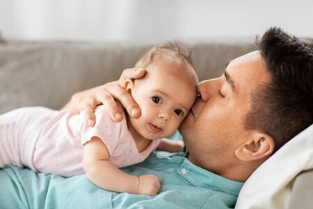 middle aged father kissing baby daughter at home