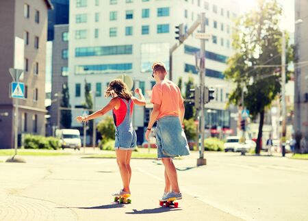Teenage couple riding skateboards on city streetの写真素材