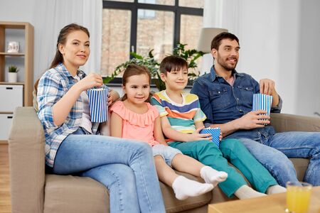 Happy family with popcorn watching tv at homeの写真素材