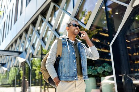 Man with backpack calling on smartphone in city