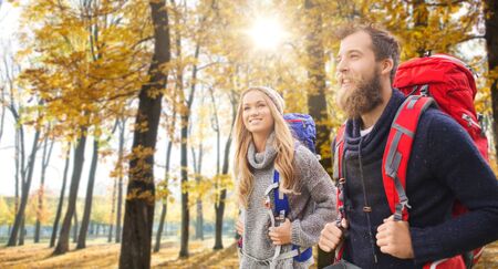 Smiling couple with backpacks hiking in autumnの写真素材