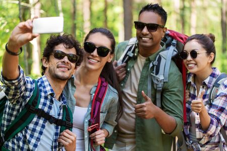 friends with backpacks hiking and taking selfieの写真素材