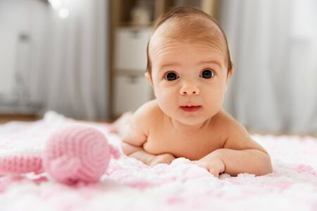 babyhood and people concept - sweet little baby girl lying on knitted pink blanket of plush yarnの写真素材