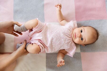 baby girl lying on blanket and mothers handsの写真素材