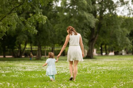 Family, childhood and parenthood concept - Mother with little baby daughter walking at summer parkの写真素材