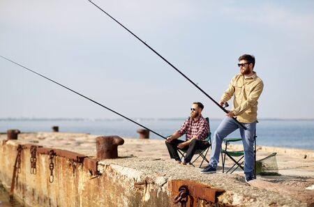 happy friends with fishing rods on pier