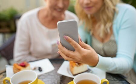 daughter and senior mother taking selfie at cafeの写真素材