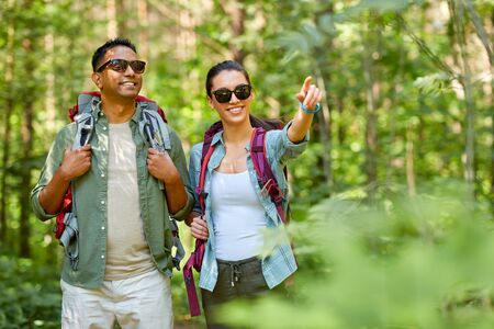 mixed race couple with backpacks hiking in forestの写真素材
