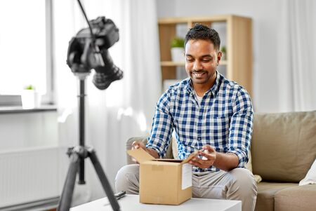 male video blogger opening parcel box at home