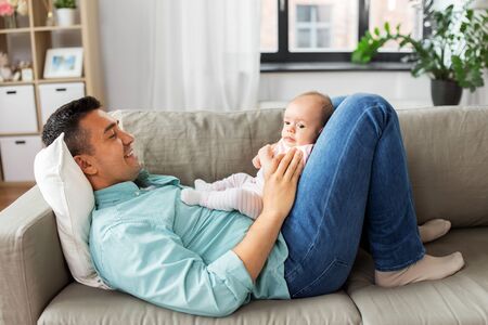 middle aged father with baby lying on sofa at home