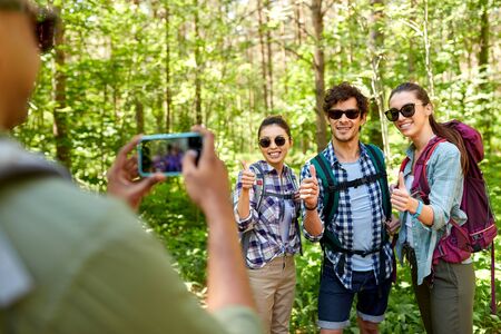 friends with backpacks being photographed on hikeの写真素材