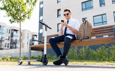 businessman with smartphone, backpack and scooterの写真素材