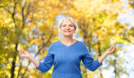 smiling senior woman chilling in autumn parkの写真素材