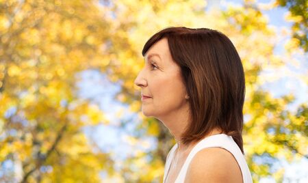 profile of senior woman over autumn trees