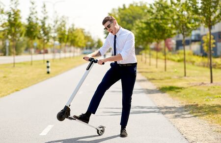 young businessman riding electric scooter outdoorsの写真素材