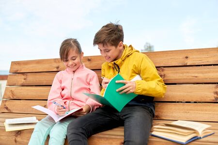 school children with notebooks sitting on bench