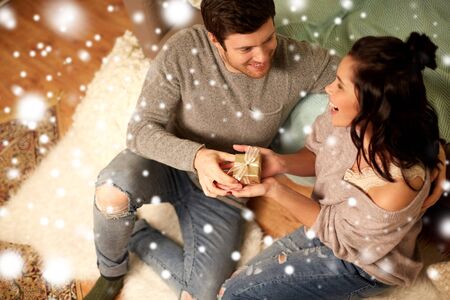 happy couple with gift box at homeの写真素材
