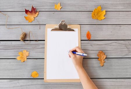 hand writing on white paper on clipboard in autumn